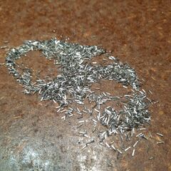 A workbench covered with hundreds of tiny metal pins: excess length that has been snipped off by hand